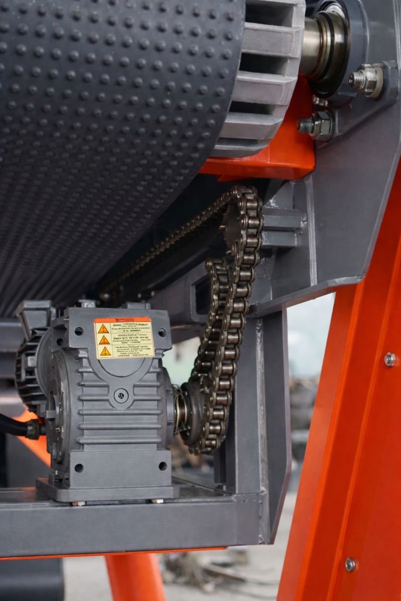 Conveyor drive system with electric motor, gearbox, and chain drive powering a textured belt roller.